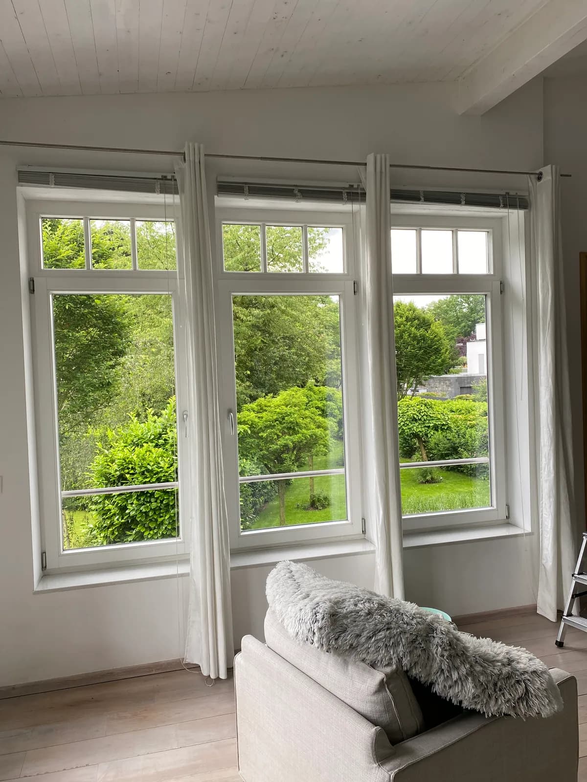 A three-part home window overlooking a garden